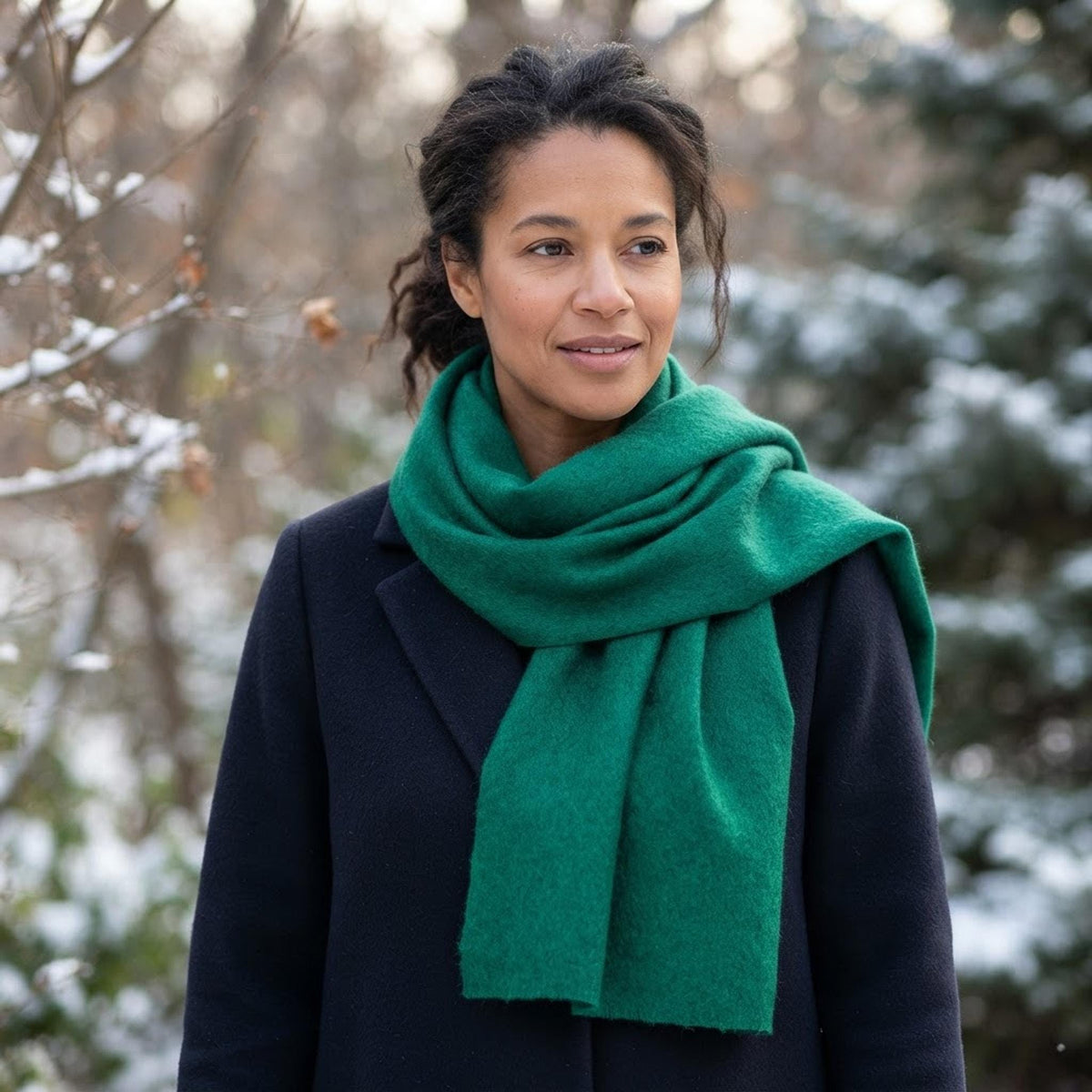 Woman in the snow wearing a green Winterborn alpaca scarf